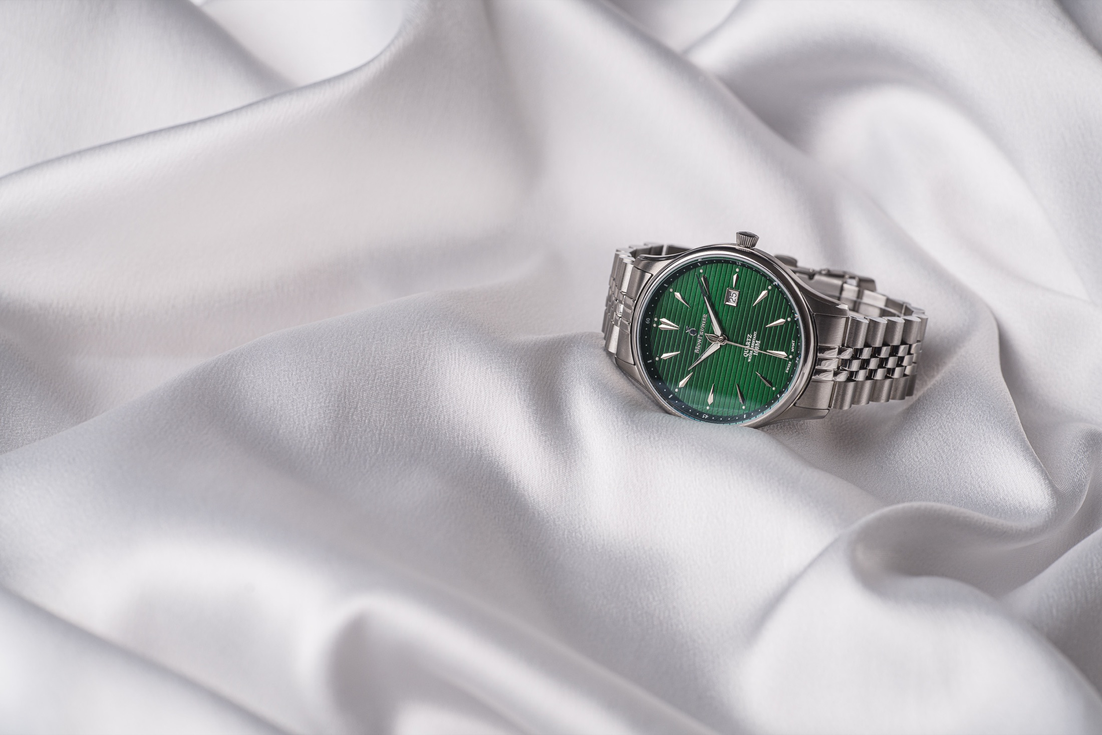 Royal Green watch resting on white silk